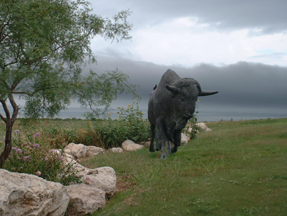 Bison sculpture with storm clouds in the distance